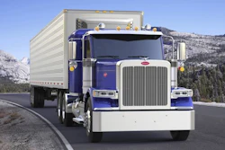 Blue and white Peterbilt semi-truck with cargo trailer driving on mountain highway