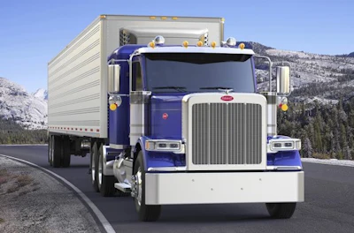 Blue and white Peterbilt semi-truck with cargo trailer driving on mountain highway