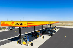 Love's Travel Stops gas station with yellow and red canopy, fuel pumps, and vehicles parked in an arid landscape.