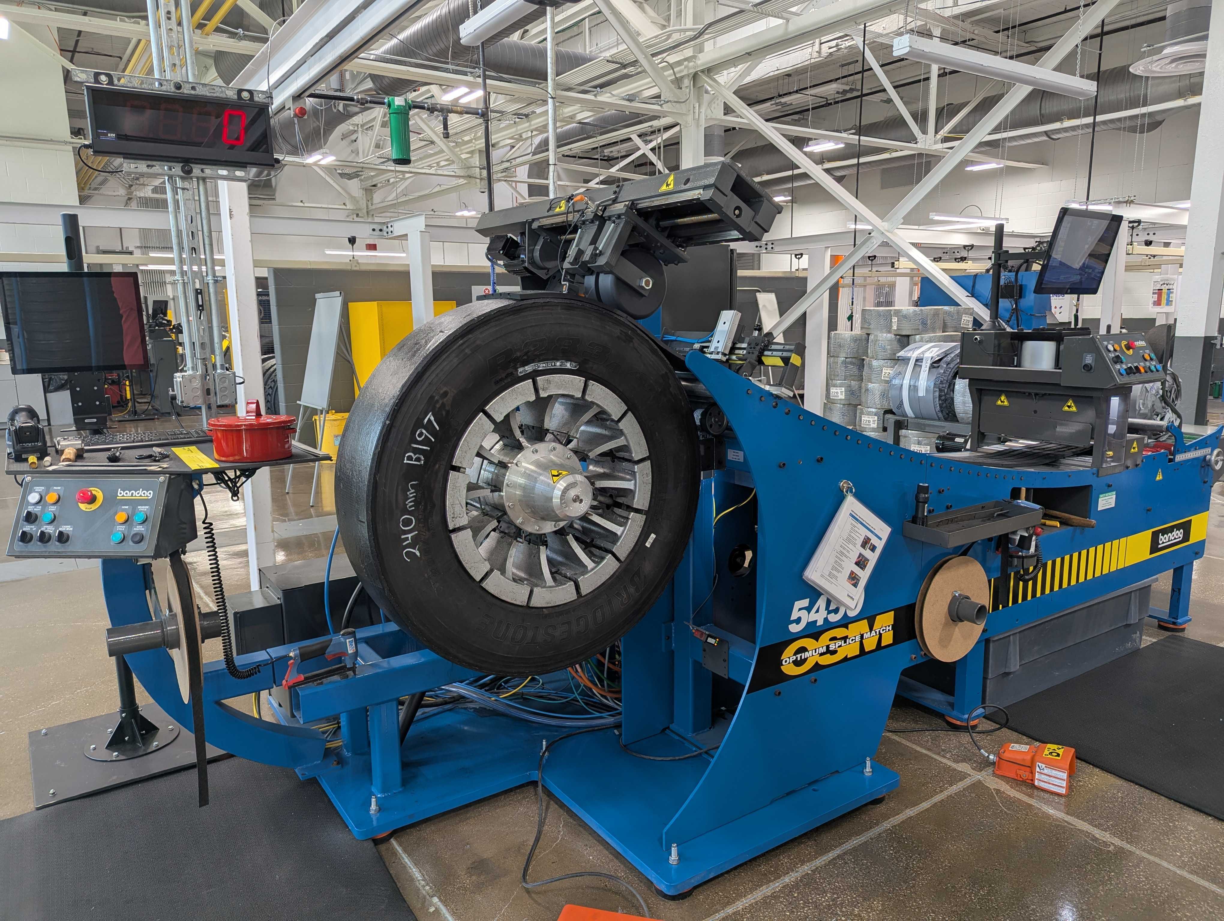 Blue ESCO tire balancing machine with mounted black tire in industrial manufacturing facility