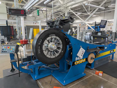 Blue ESCO tire balancing machine with mounted black tire in industrial manufacturing facility