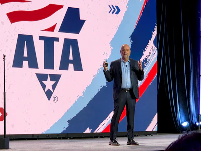 Professional speaker presenting at podium with ATA logo displayed on stage backdrop
