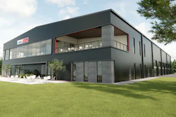 Modern two-story dark gray residential building with large windows, terrace, and manicured lawn