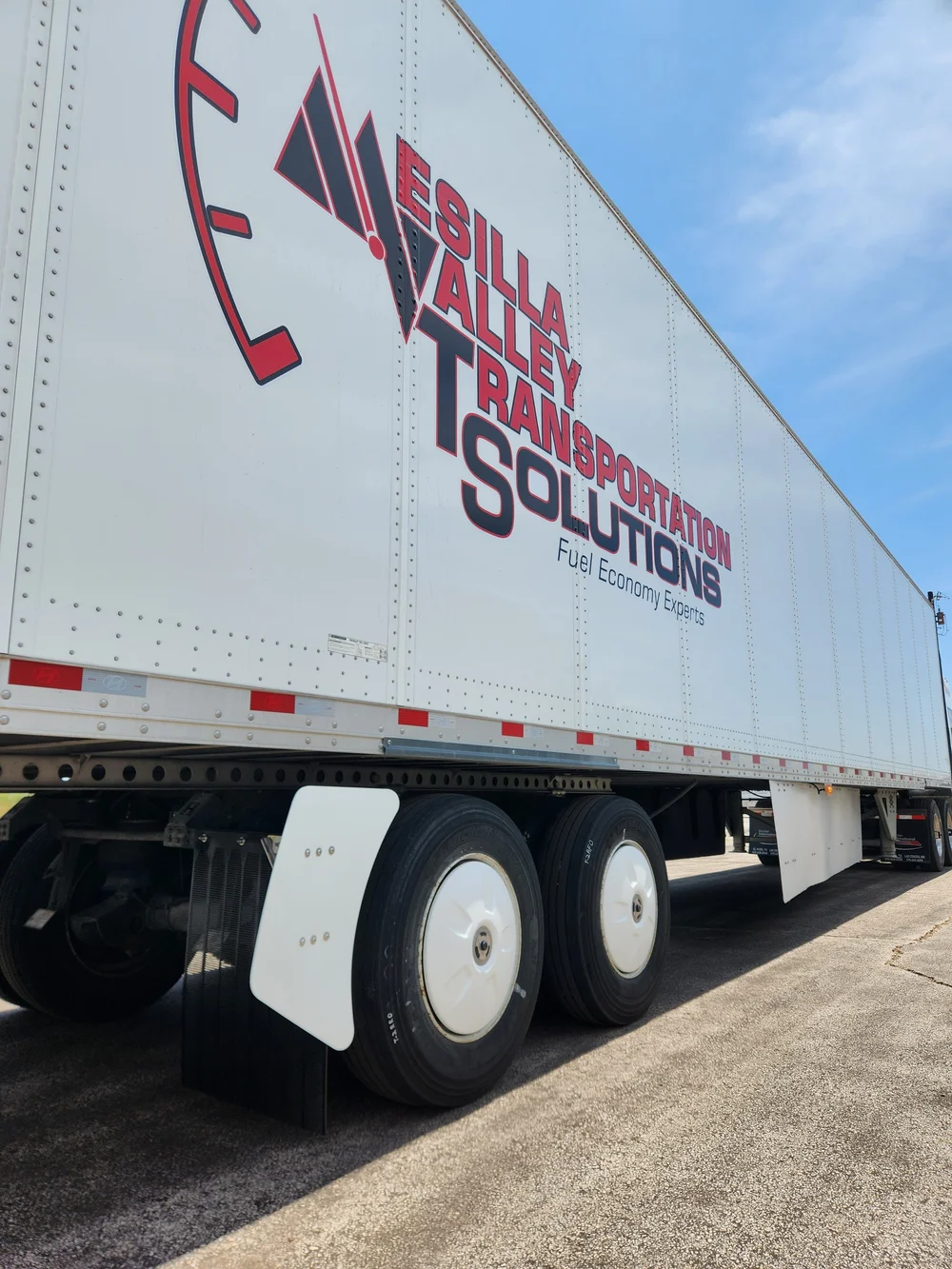 Bella Valley Transportation Solutions semi-truck trailer with red and blue branding and fuel economy tagline