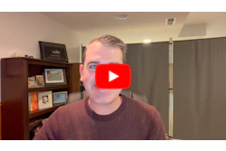 Man in burgundy sweater speaking to camera with YouTube play button overlay in office setting