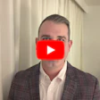 Professional man in plaid blazer with YouTube play button overlay indicating video content