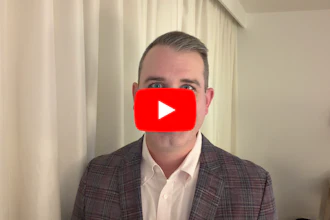Professional man in plaid blazer with YouTube play button overlay indicating video content