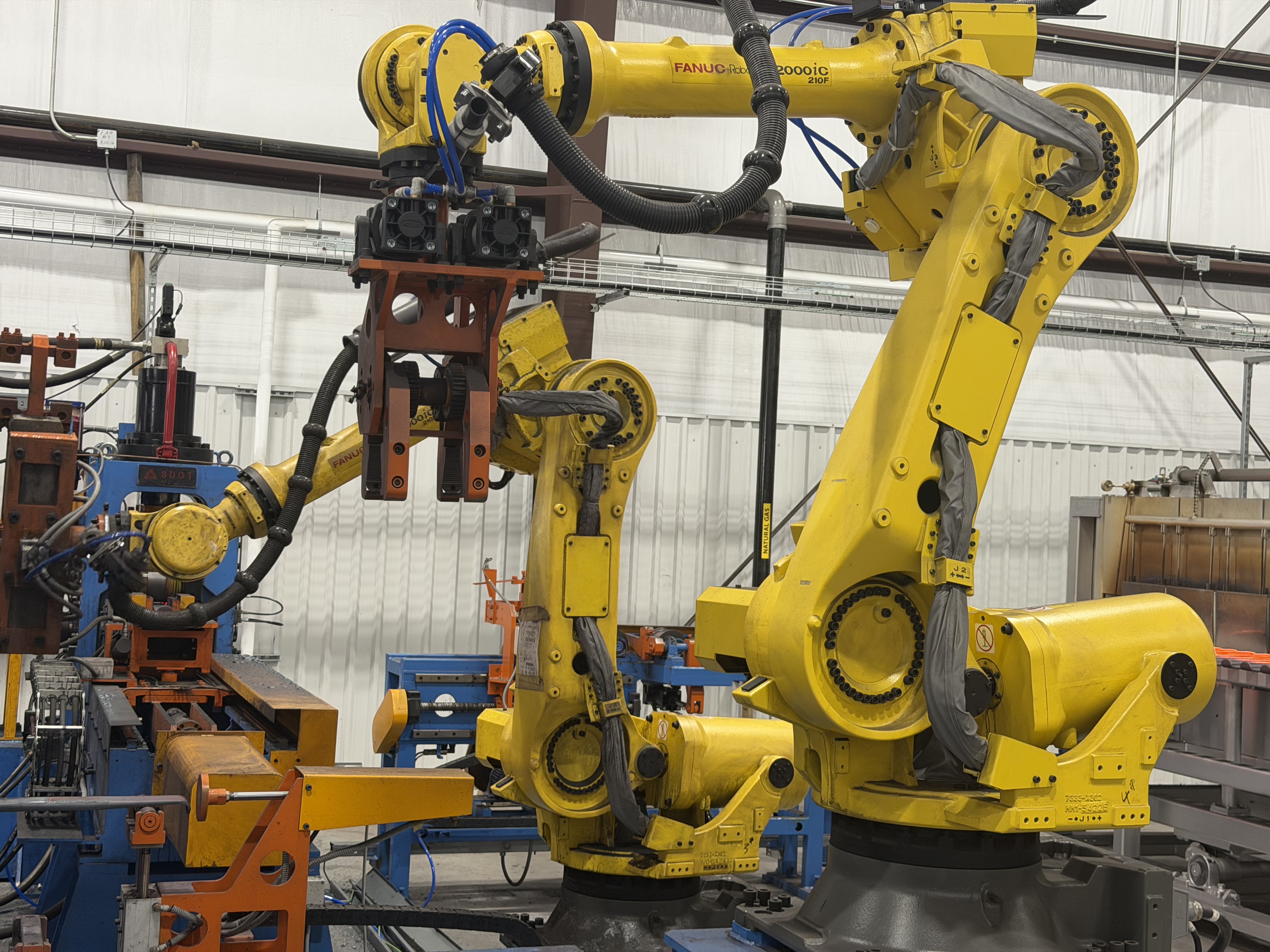 Industrial robotic arms and automated manufacturing equipment in a warehouse facility