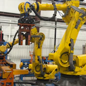 Industrial robotic arms and automated manufacturing equipment in a warehouse facility