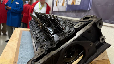 Disassembled engine cylinder head with valve springs displayed at industrial exhibition