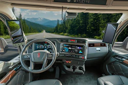 Interior view of commercial truck cabin with steering wheel, dashboard, and mountain landscape visible through windshield