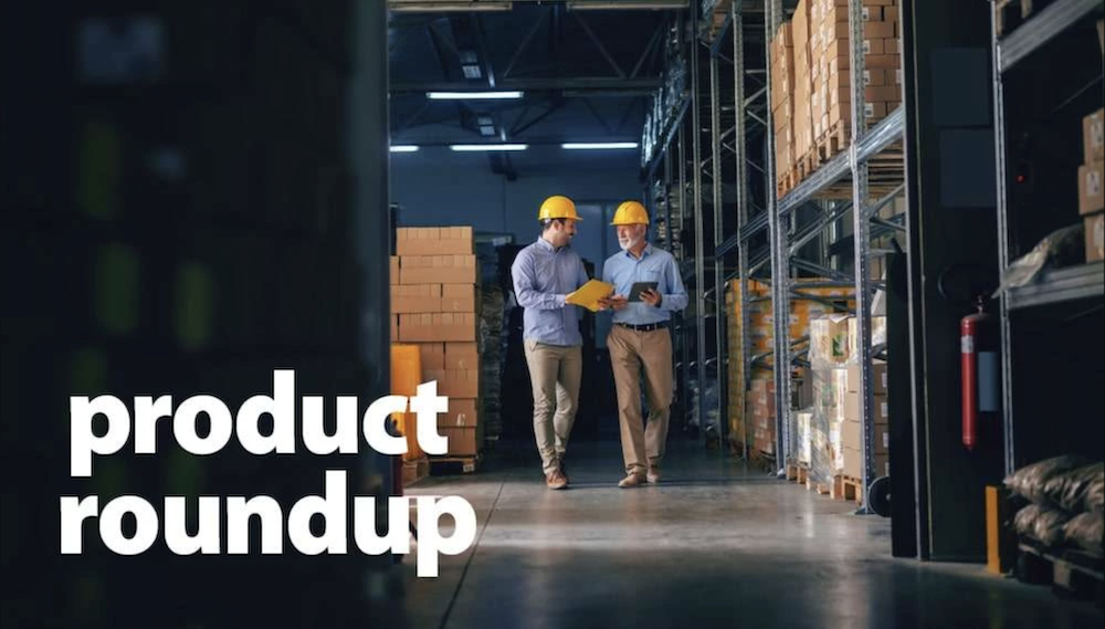 Two warehouse workers in hard hats walking through storage facility with cardboard boxes and metal shelving