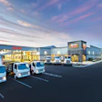 Isuzu commercial vehicle dealership facility at dusk with three white delivery trucks parked in front of modern building