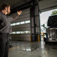 Mechanic gesturing in truck garage with commercial vehicle in background