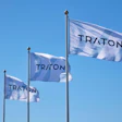 Three blue and white TRATON corporate flags flying against a clear sky
