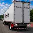 Truck Lite branded commercial delivery truck with red and white cargo box on highway
