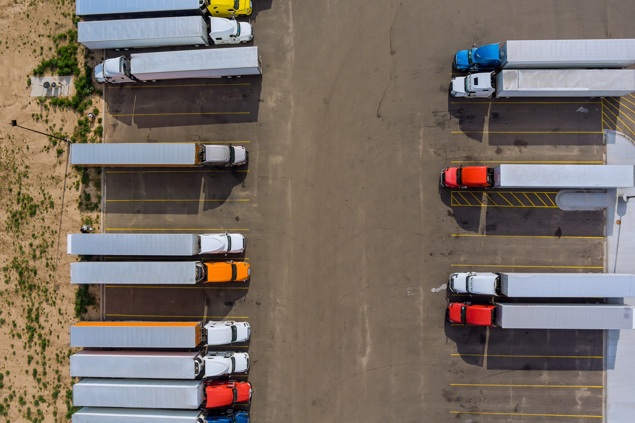 Aerial view of semi-trucks parked in organized rows at a logistics depot facility