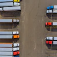 Aerial view of semi-trucks parked in organized rows at a logistics depot facility
