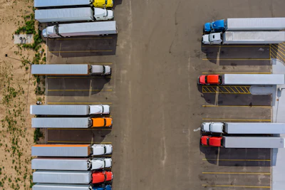 Aerial view of semi-trucks parked in organized rows at a logistics depot facility
