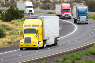 Yellow semi-truck leading convoy of commercial trucks on multi-lane highway through desert landscape