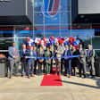 People standing in front of a building, cutting a ribbon