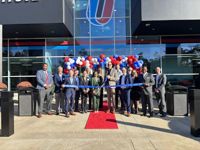 People standing in front of a building, cutting a ribbon